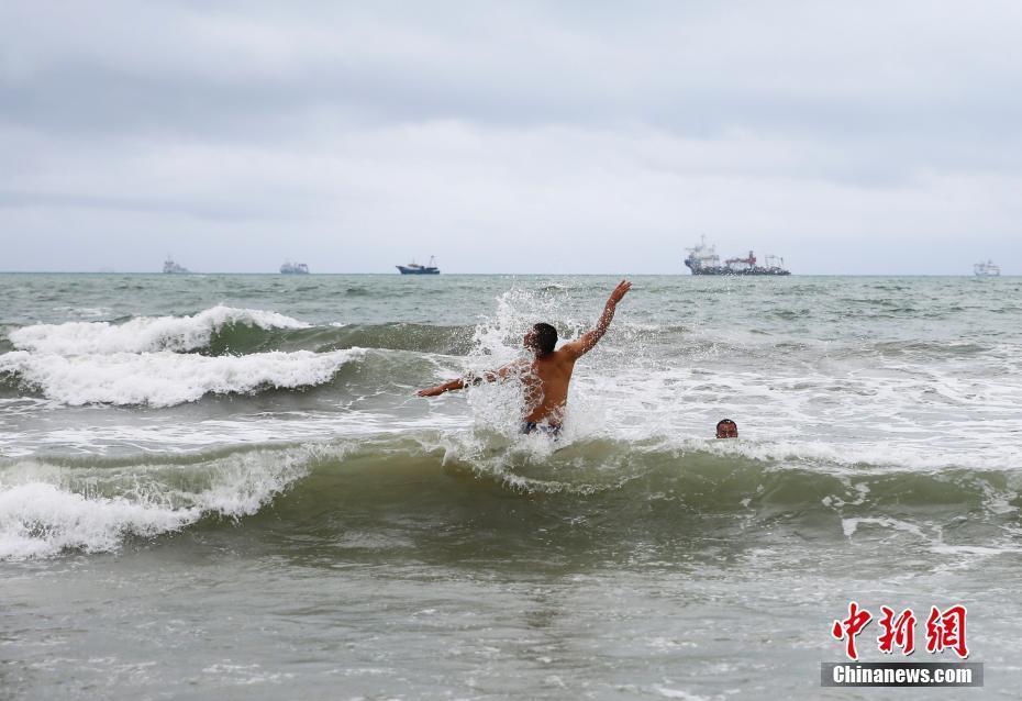 臺(tái)風(fēng)“山神”橫穿海南 游客不懼風(fēng)雨海邊戲水