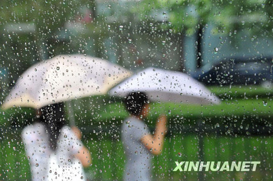 7月17日,游客走在雨中的北京街头.